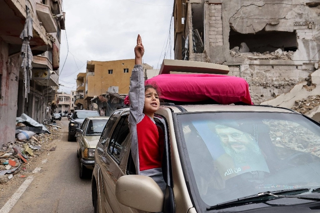 Una niña hace un gesto mientras está sentada en un automóvil decorado con un retrato del líder asesinado de Hezbollah, Hassan Nasrallah, mientras las personas desplazadas regresan a sus hogares en el sur del Líbano después de que entrara en vigor un alto el fuego entre Israel y Hezbollah, el 27 de noviembre de 2024. Foto AFP 
