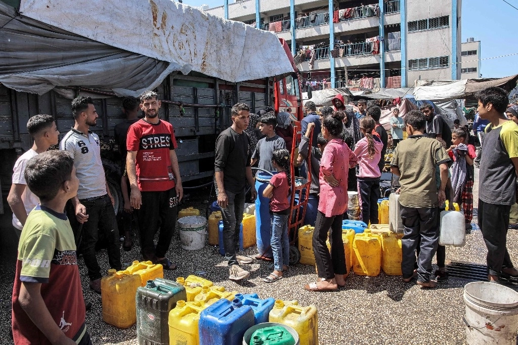 Jóvenes se reúnen para recolectar agua en el patio de una escuela de la Agencia de la ONU para Refugiados Palestinos, en Jabalia, al norte del territorio palestino. Foto Afp 