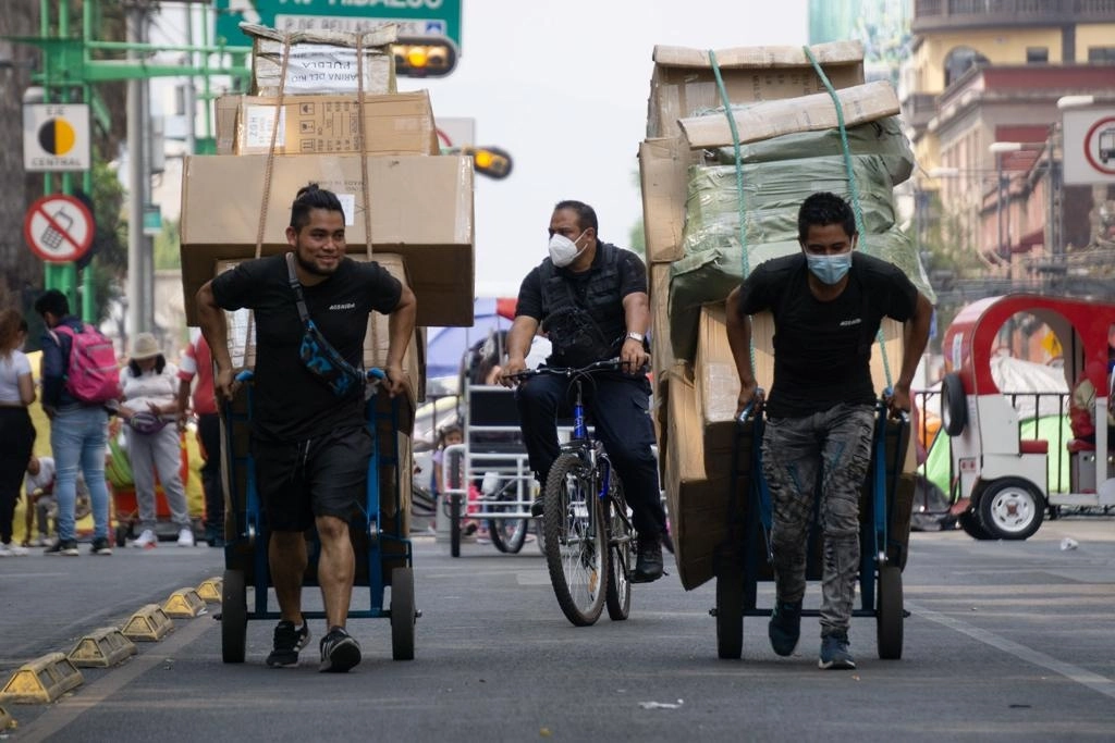 Un par de diableros transportan mercancía sobre Eje Central, cuya circulación se encuentra detenida por una manifestación de artesanos triquis, en el Centro Histórico de la Ciudad de México, el pasado 16 de abril. Foto Pablo Ramos