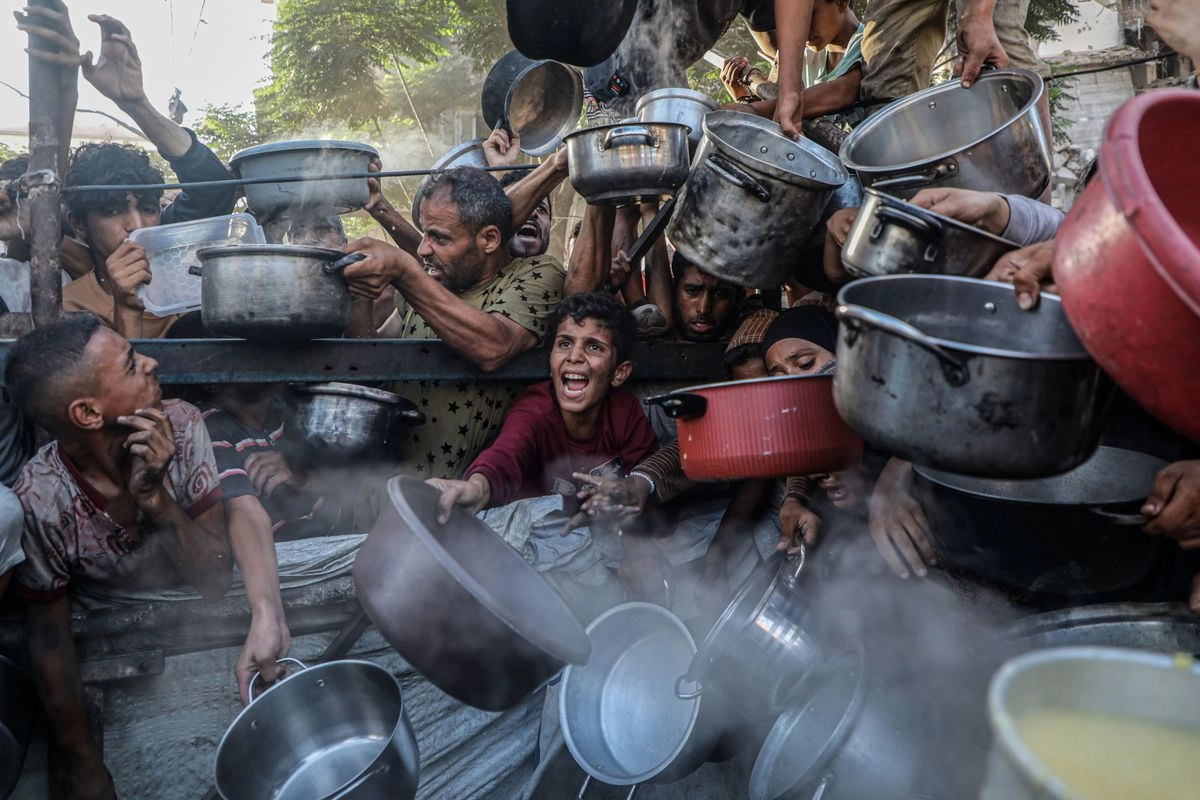 Palestinos desplazados esperan recibir comida en un centro de distribución de alimentos, en la Ciudad de Gaza. 
