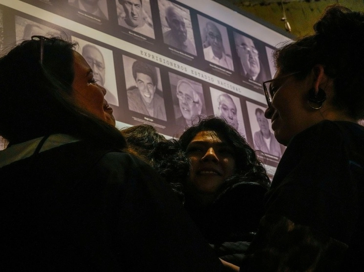Nietas de Héctor Benavides, quien fue detenido y torturado por tres años durante la dictadura del general Augusto Pinochet, abrazan a su madre  frente al retrato de su abuelo, durante una vigilia en el marco del 50 aniversario del golpe militar chileno de 1973, el 11 de septiembre de 2023. Foto Ap