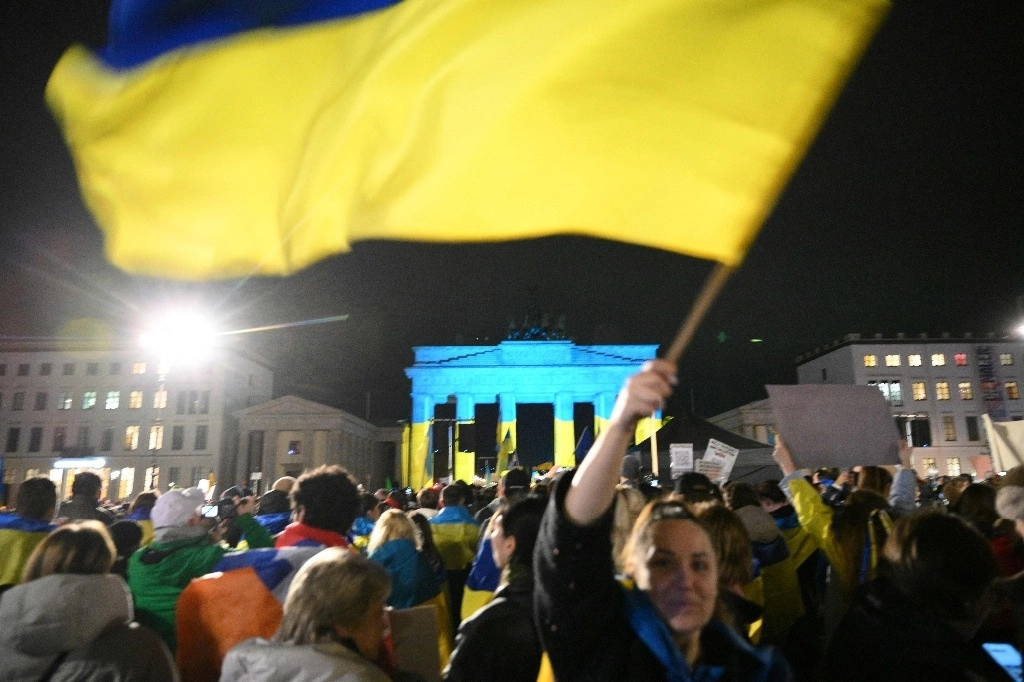 Manifestantes participan en una manifestación a favor de Ucrania frente a la Puerta de Brandeburgo, iluminada con los colores de la bandera ucraniana, en conmemoración de los tres años de la invasión rusa bajo el lema "Vote por Ucrania", en Berlín, el 24 de febrero de 2025. Foto Afp