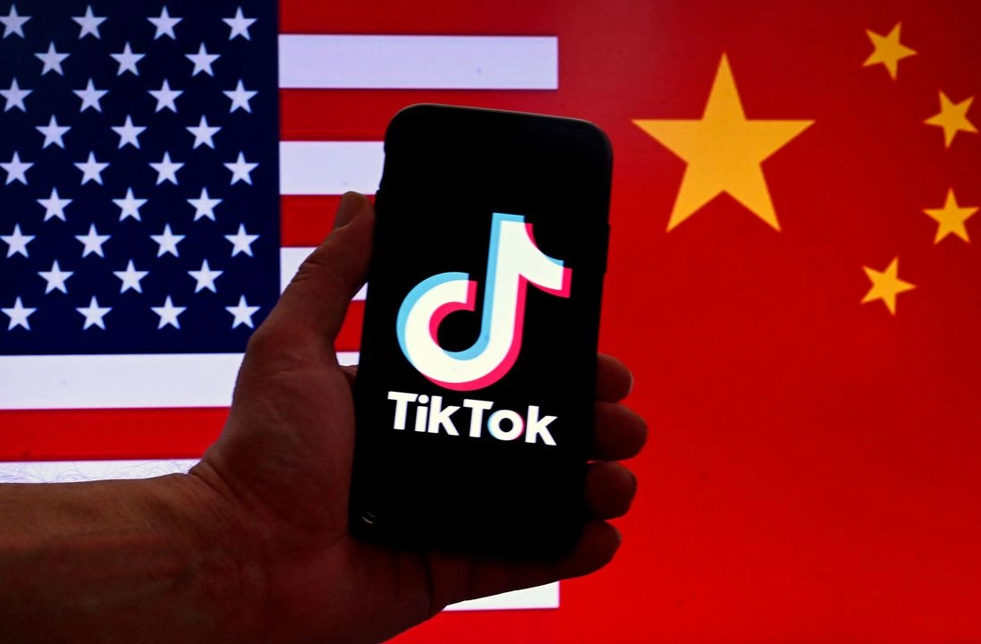 El logotipo de la aplicación TikTok aparece en la pantalla de un iPhone frente a una bandera estadounidense con una bandera china como fondo. Foto