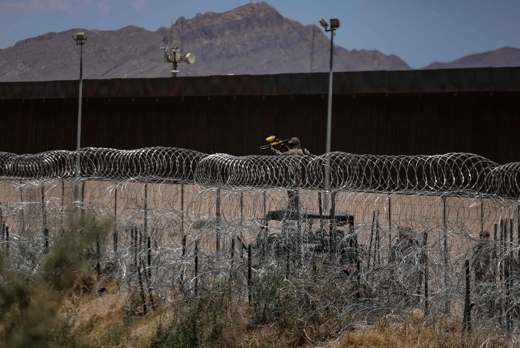 Agente de la Guardia Nacional de Texas dispara su arma no letal para dispersar a migrantes que intentan cruzar desde el Río Bravo en Cd. Juárez, Chihuahua. Foto Afp
