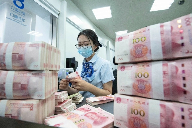 Una empleado cuenta billetes de 100 yuanes en un mostrador bancario en la provincia oriental china de Jiangsu. Foto Afp 




