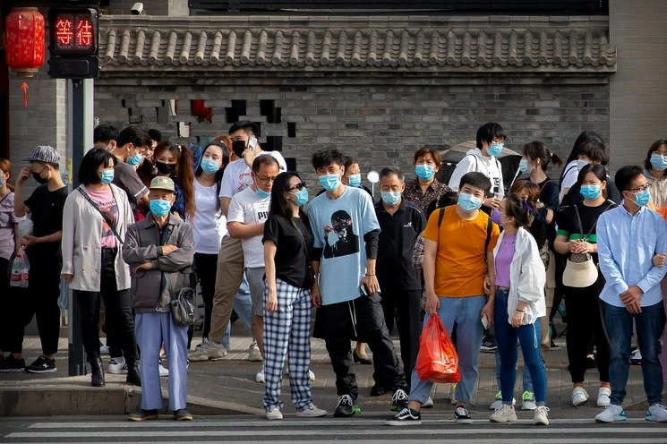 Personas esperan para cruzar una intersección en Beijing, China. Foto Mark Schiefelbein / Ap