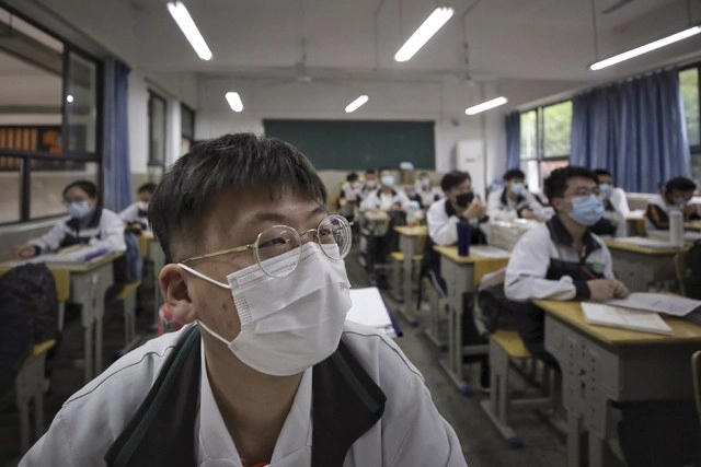 Estudiantes con cubrebocas toman clase en una secundaria de Wuhan, China. Foto Ap