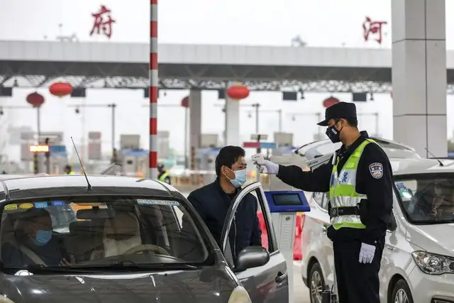 Un policía revisa la temperatura de un conductor en un punto de revisión en Wuhan, China. Foto Ap 