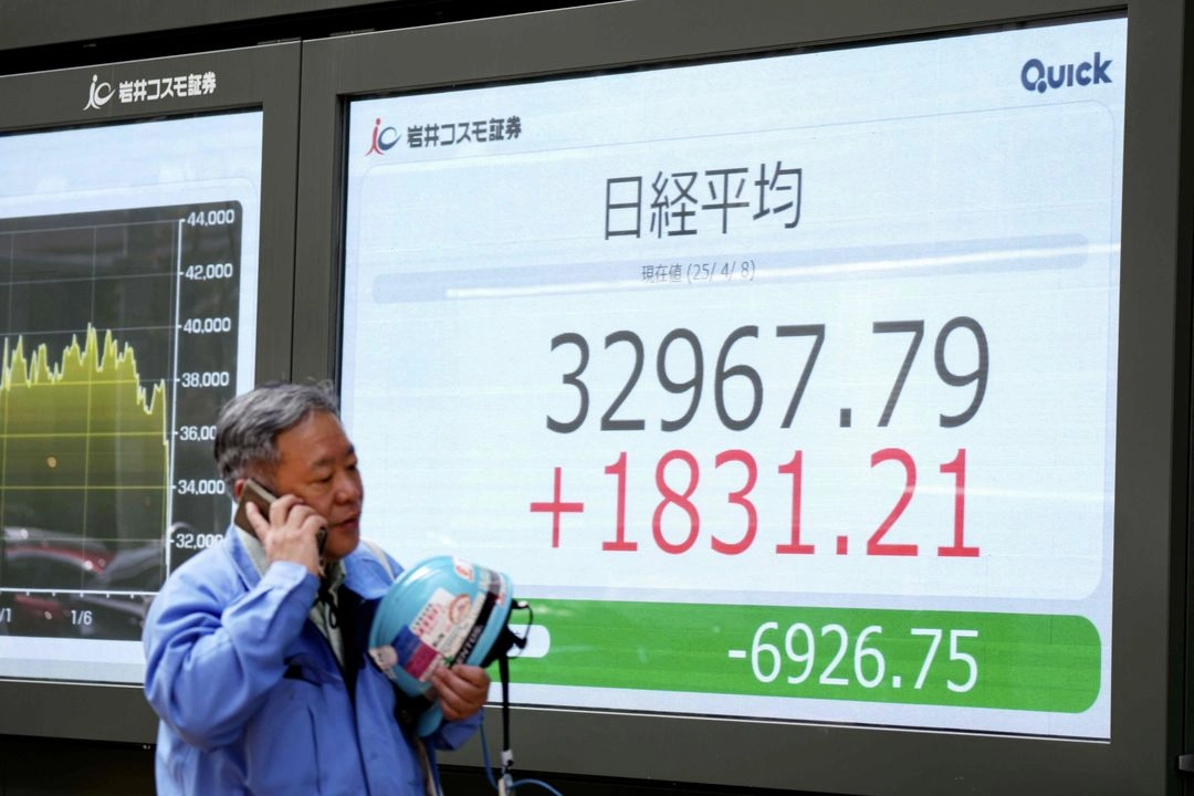 Un hombre pasa junto a un tablero electrónico que muestra las cifras del Nikkei Stock Average de la Bolsa de Tokio, en una calle de Tokio.