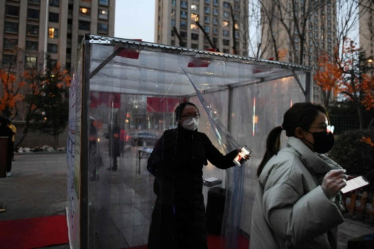 Habitantes de Beijing salen de un módulo de desinfección establecido como medida de protección contra el coronavirus COVID-19 en la entrada de un complejo en Tongzhou, al este de la capital china. Foto Afp 
