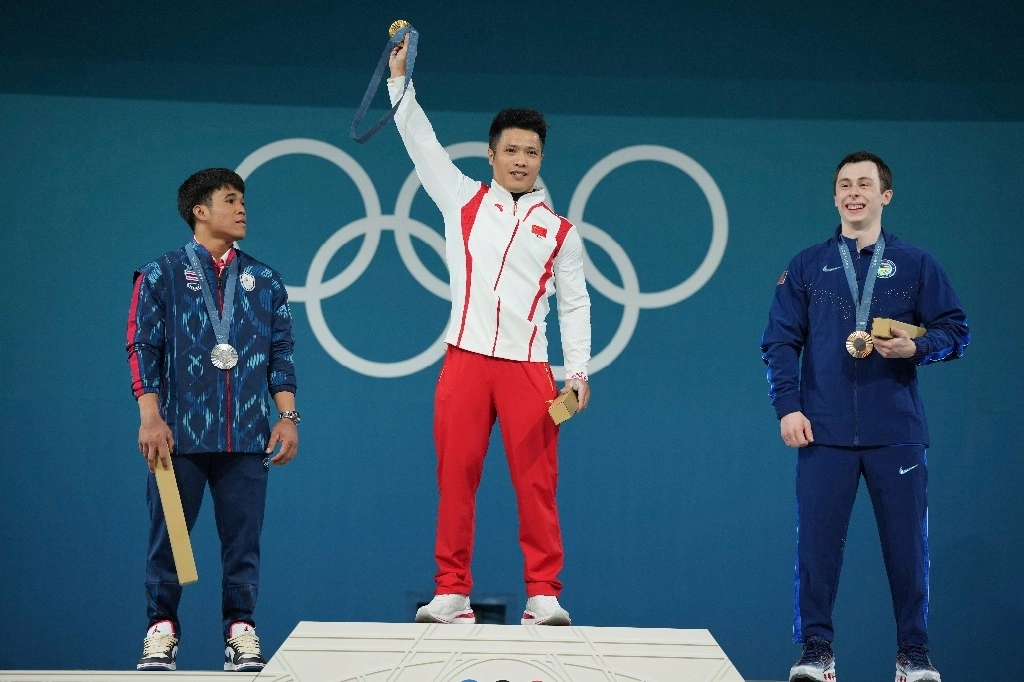 Los medallistas, de izquierda a derecha, Theerapong Silachai de Tailandia (plata), Li Fabin de China (oro) y Hampton Morris de Estados Unidos (bronce) celebran en el podio. Foto Ap