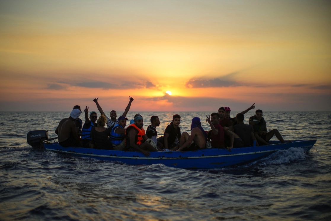 Migrantes de Túnez gesticulan mientras navegan en un bote de madera mientras son asistidos por miembros de la tripulación de la ONG española Open Arms. Foto Ap