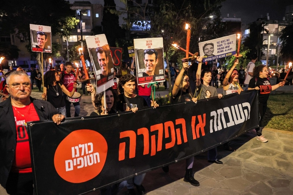Los manifestantes marchan con carteles y antorchas durante una manifestación de los familiares de los rehenes tomados cautivos por militantes palestinos en la Franja de Gaza durante los ataques del 7 de octubre, y sus partidarios, exigiendo acciones para liberarlos frente a la base de Kirya que alberga la sede del Ministerio de Defensa israelí en Tel Aviv el 18 de abril de 2024. Foto Afp