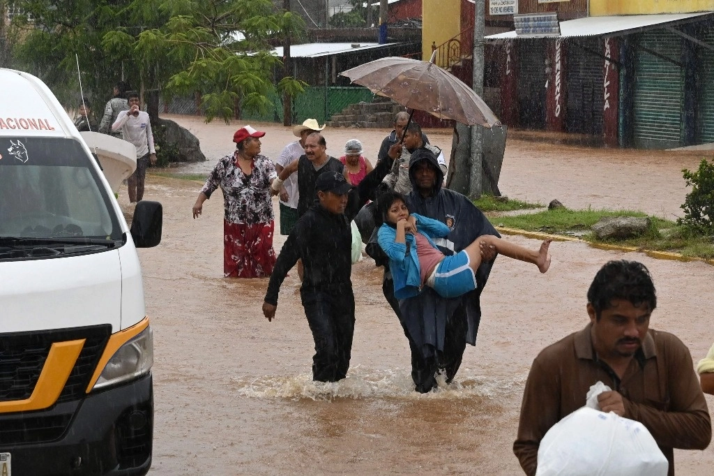 La gente camina por una calle inundada tras el paso del huracán John por Acapulco, México, el 26 de septiembre de 2024. Foto Afp
