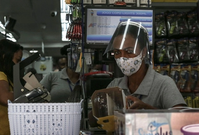Con careta y cubrebocas, una mujer realiza su jornada laboral en una tienda de Sao Paulo, Brasil. Foto Xinhua