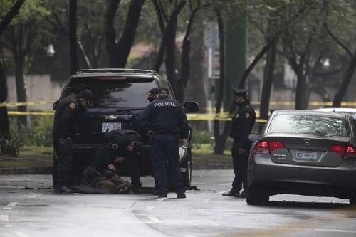 Peritos de la Policía de Investigación revisan los chalecos antibalas hallados debajo de una camioneta que utilizaron los sicarios. Foto La Jornada