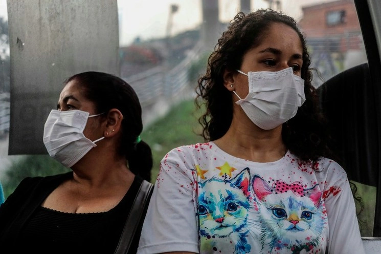 Mujeres utilizan cubrebocas mientras caminan por calles de Medellín, Colombia. Foto Afp