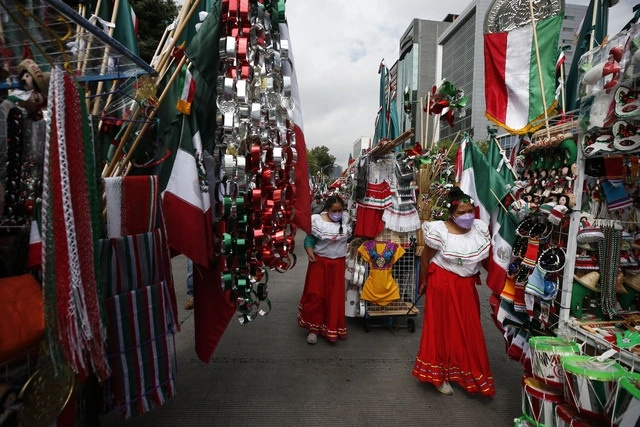 Vendedoras de adornos patrios caminan hacia el Zócalo, para pedir espacio para ofrecer sus productos, en imagen de antier. Foto Alfredo Domínguez 
