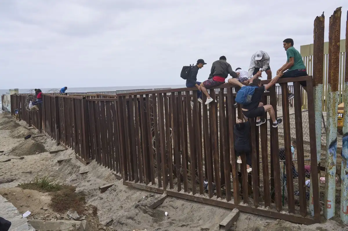 Un grupo de migrantes cruza el muro fronterizo en la ciudad de Tijuana.
