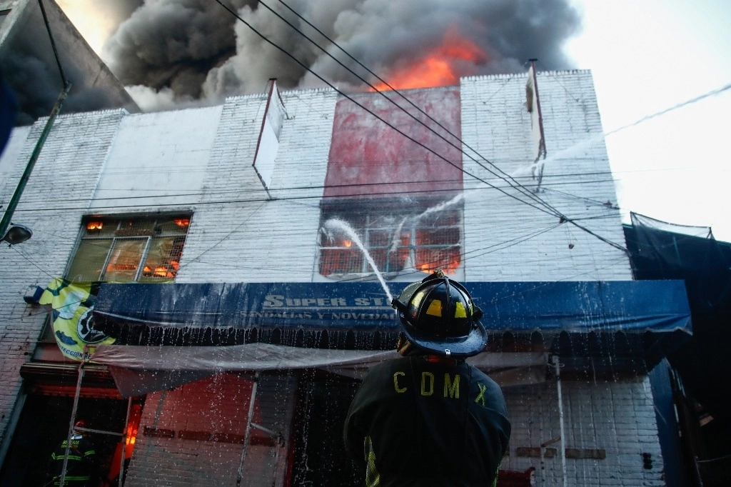 Bomberos de la ciudad de México, intentan apagar el incendio que se registró el 16 de noviembre pasado en una bodega de calzado en el barrio Tepito. Foto Victor Camacho