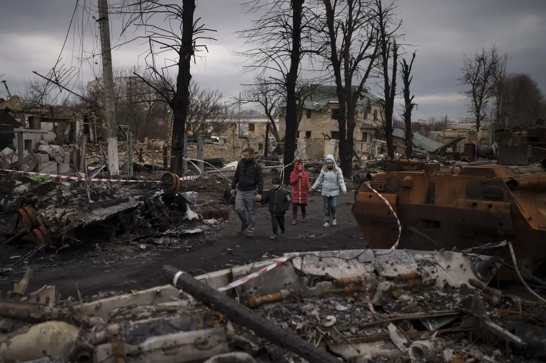 Una familia camina entre tanques destruidos en Bucha, a las afueras de Kiev, en Ucrania, el 6 de abril de 2022. Foto Ap 