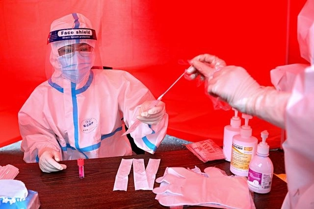 Un trabajador médico recolecta una muestra de una persona para hacer la prueba del coronavirus, en Mudanjiang, China. Foto Afp 