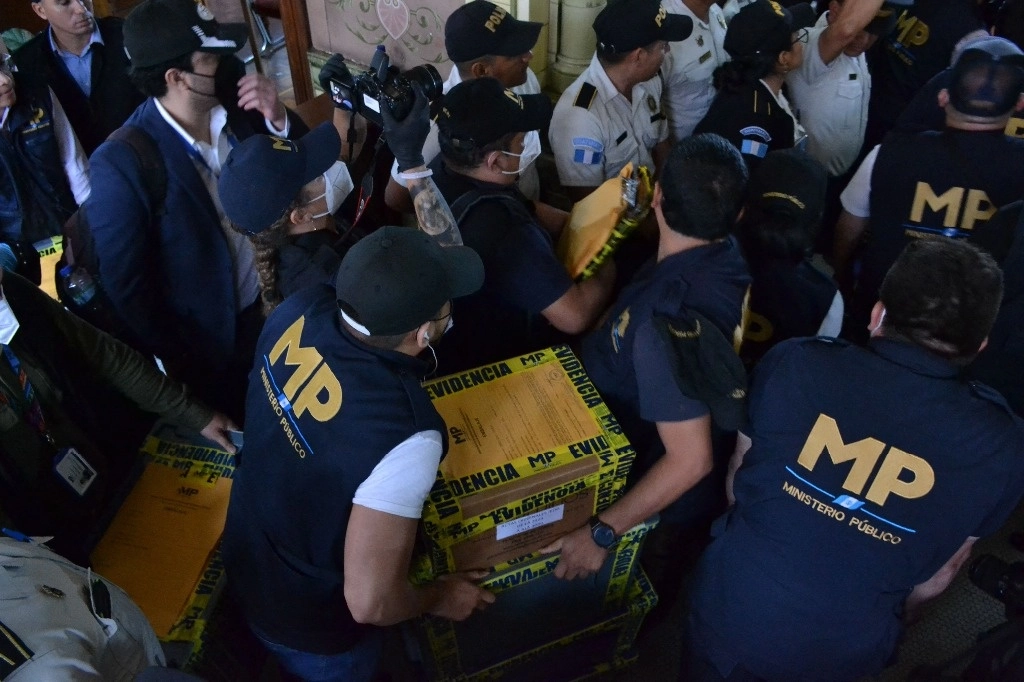 Esta imagen publicada por el Tribunal Supremo Electoral de Guatemala muestra a fiscales del Ministerio Público llevando cajas que contienen actas de recuento de las elecciones presidenciales. Foto Afp