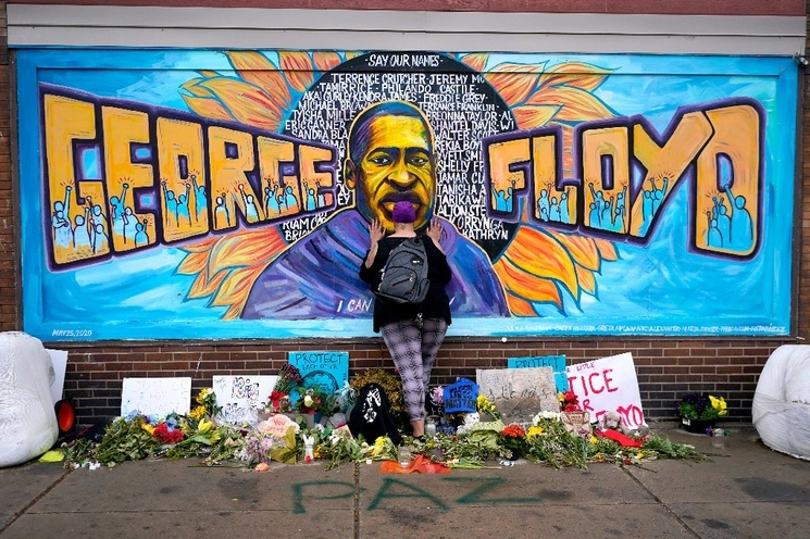 Damarra Atkins rinde homenaje a George Floyd frente a un mural con la imagen del ciudadano estadunidense que murió tras ser detenido por un policía en mayo de 2020, en Minneapolis, EU, el 7 de agosto de 2023. Foto Ap / Archivo