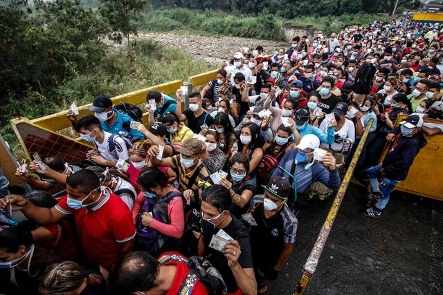 Venezolanos con tapabocas, para protegerse del coronavirus, muestran sus documentos en la frontera con Colombia, en Cúcuta. Foto Afp 
