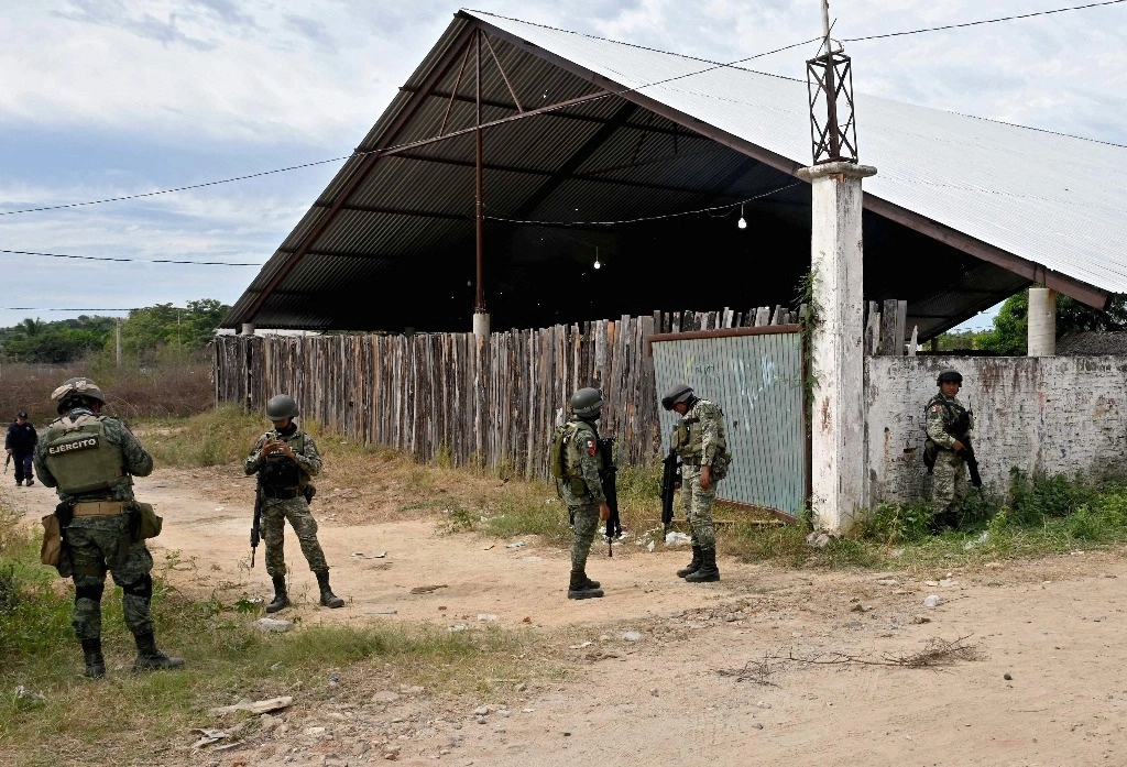 Soldados hacen guardia e inspeccionan el área afuera de un palenque, después de que 13 personas murieran y 20 resultaran heridas en un ataque de hombres armados durante una pelea de gallos, en Petatlán, Guerrero, el 7 de enero de 2024. Foto Afp
