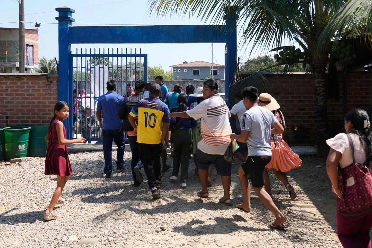 La gente se apresura dentro de un colegio electoral mientras los opositores del candidato presidencial Andrónico Rodríguez lanzan piedras después de que votara en Entre Ríos, en la región del Chapare de Bolivia, el domingo 17 de agosto de 2025. Foto