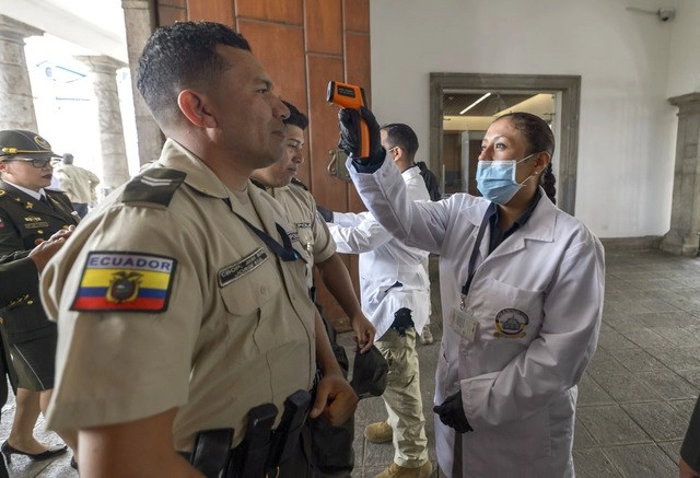 Una trabajadora de la Salud toma la temperatura a policía en Quito, Ecuador. Foto Xinhua