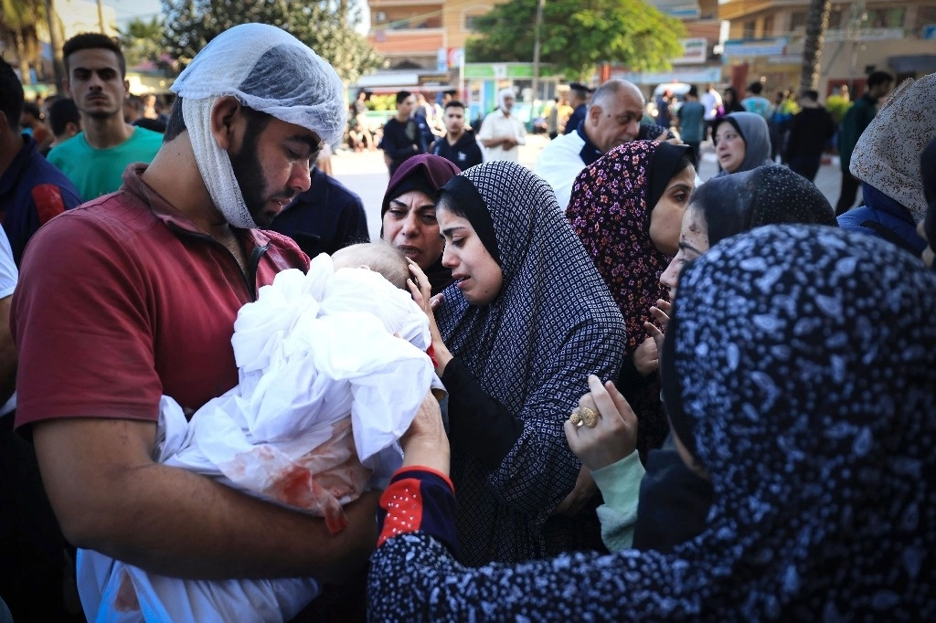 Dolientes se despiden de su bebé fallecido mientras se reúnen con el corresponsal de Al-Jazeera, Wael Al-Dahdouh, cuya familia murió durante un ataque israelí en el campamento de Nuseirat, en el sur de la Franja de Gaza, el 26 de octubre de 2023. Foto Afp