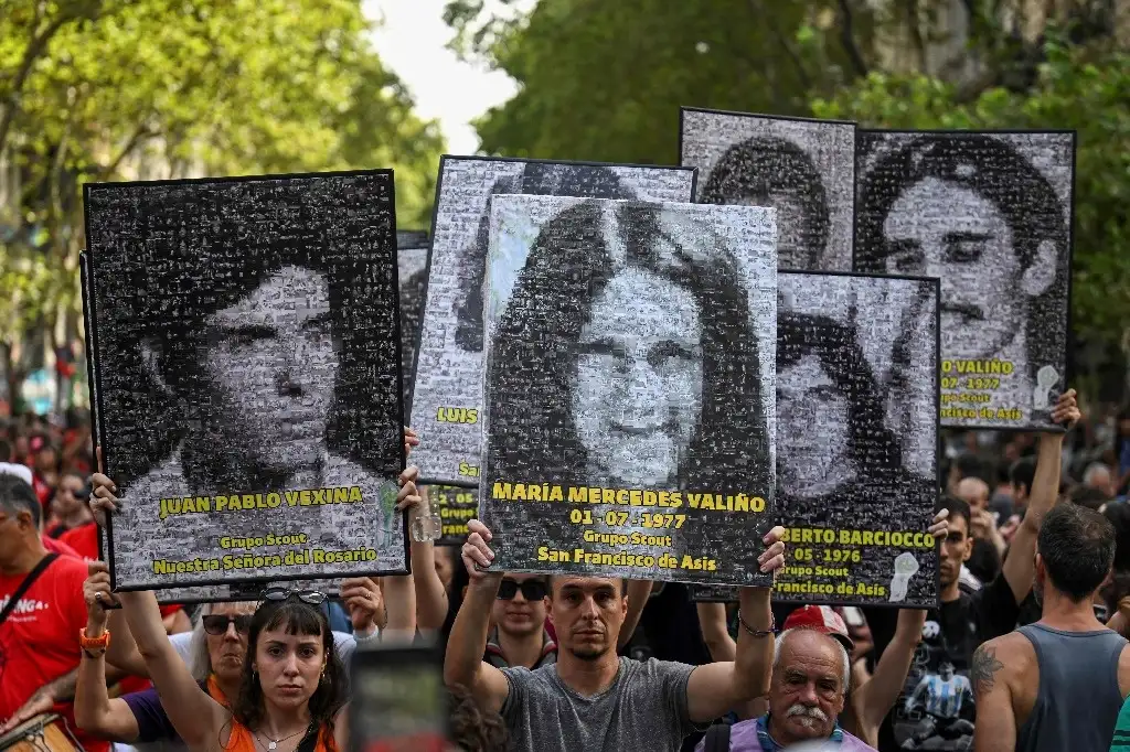 En Buenos Aires, manifestantes alzan retratos de personas desaparecidas, al conmemorar el 47 aniversario del golpe de Estado que llevó a la instauración de una dictadura militar en Argentina. Foto Afp.