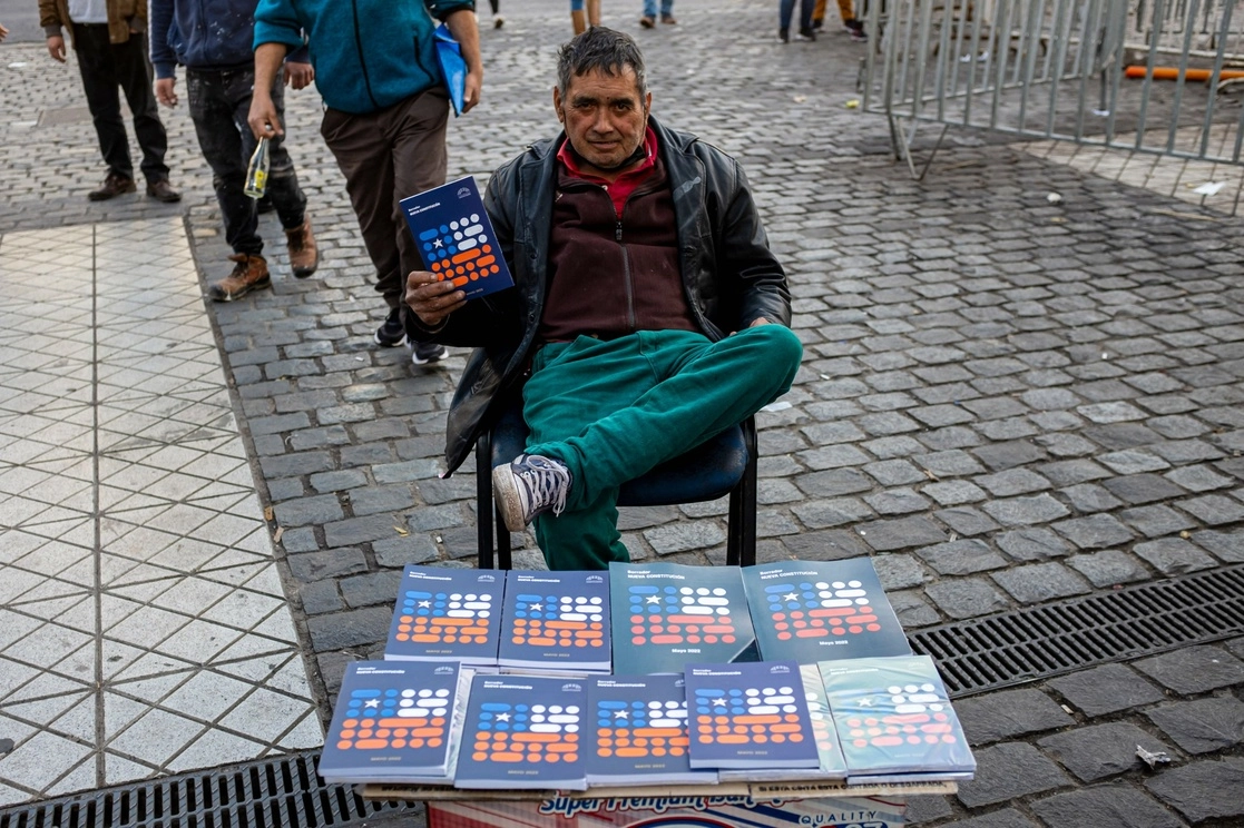 Un vendedor posa con un libro de la nueva Constitución que se vende al público en las calles de Santiago, el 12 de julio de 2022. Foto Afp