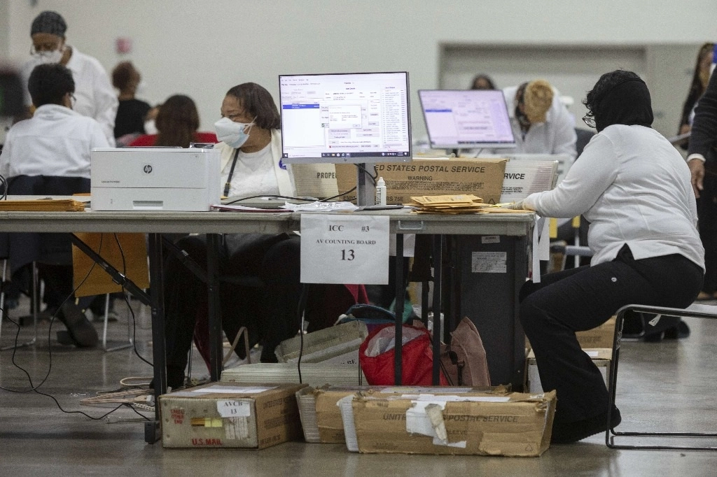 Trabajadores del Departamento de Elecciones de Detroit revisan papeletas de voto ausente en la Junta Central de Conteo en el Centro TCF. Con una participación récord en la votación anticipada, los estadunidenses acudirán a  urnas mañana para las elecciones presidenciales. Foto AFP 