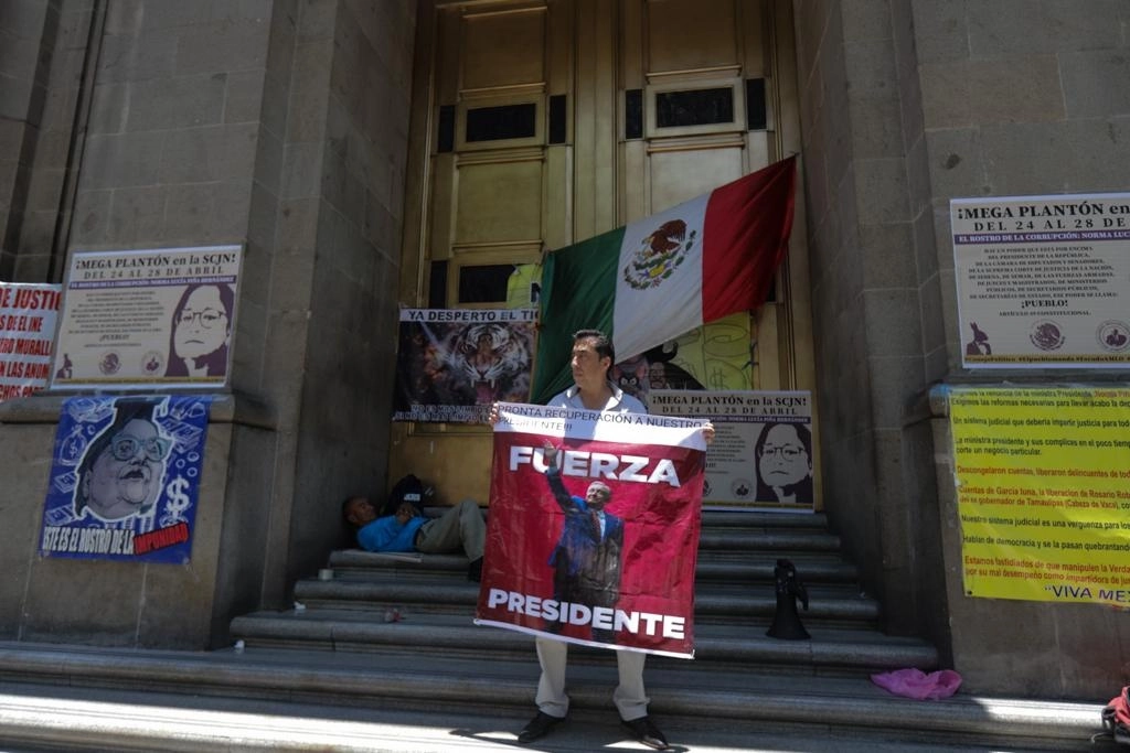 Ciudadanos escriben mensajes a los ministros y los introducen por debajo de la puerta de la Suprema Corte de Justicia de la Nación, en la capital del país, el 25 de abril de 2023. Foto Pablo Ramos