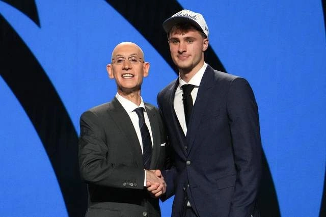 El basquetbolista Cooper Flagg (der) estrecha la mano del comisionado de la NBA, Adam Silver (izq) tras ser seleccionado por los Dallas Mavericks. Foto 