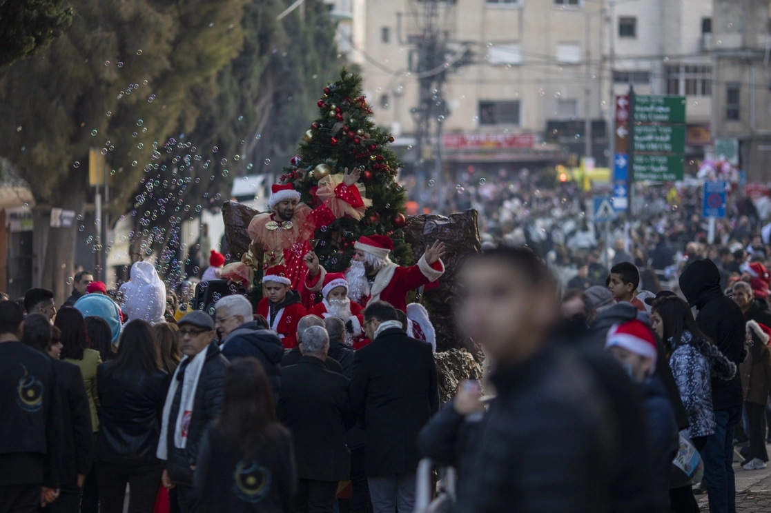 Personas caminan en la ciudad de Nazaret mientras se realiza un desfile navideño, en esta ciudad de Israel, el 24 de diciembre de 2021. Foto Ap