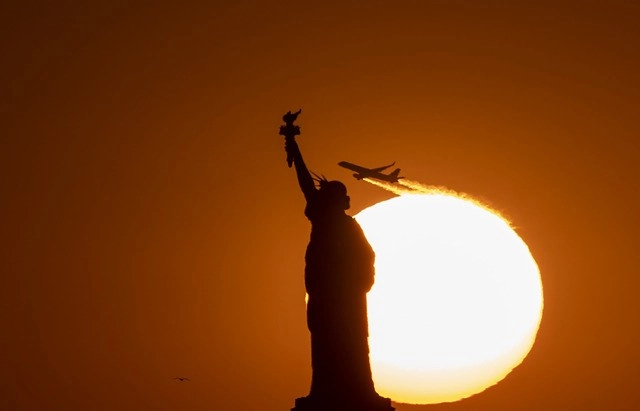 La cancelación de puestos de trabajo afecta a todos los niveles de la industria y aumenta su ritmo en la medida en que los países cierran sus fronteras para combatir el virus. En la imagen, un avión vuela detrás de la Esratua de la Libertad al atardecer. Foto Afp 