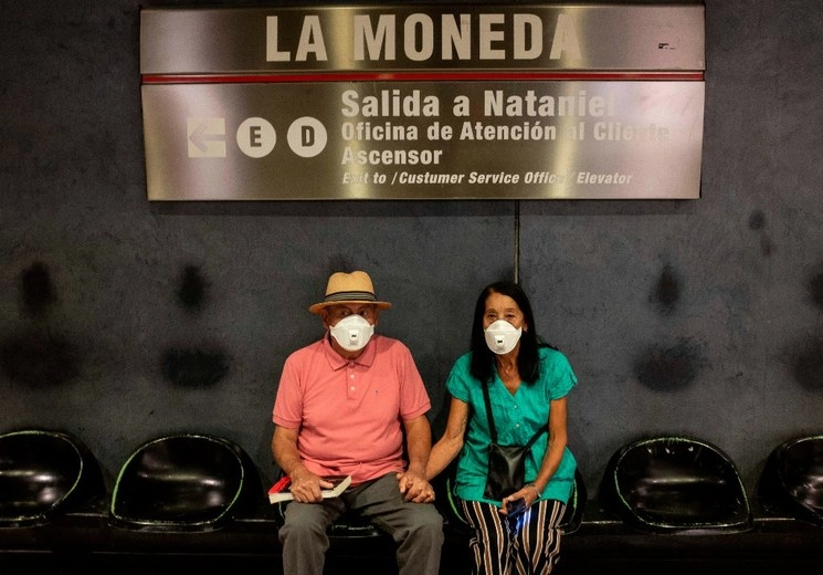 Viajeros usan mascarillas como medida de precaución contra la propagación del coronavirus, mientras esperan el metro en la estación La Moneda en Santiago. Foto AFP 