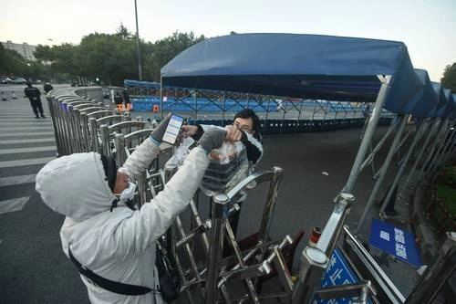 En Hangzhou, China, un universitario recibe su pedido de comida según los lineamientos sanitarios por el rebrote. Foto Afp