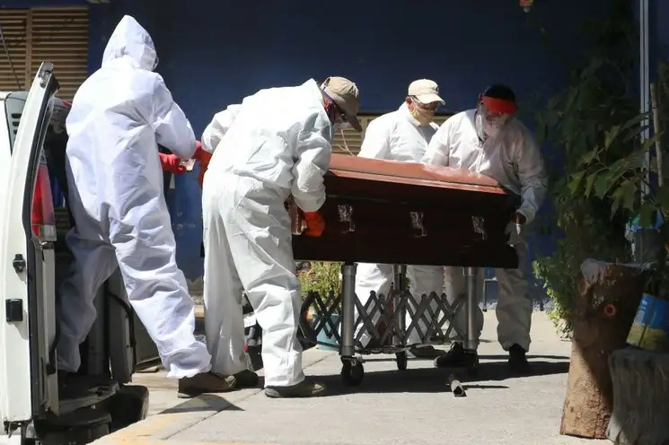 Cremadores del Panteón Xilotepec, en Xochimilco, manejan el féretro de una persona que murió a causa de Covid-19. Foto Cuartoscuro 