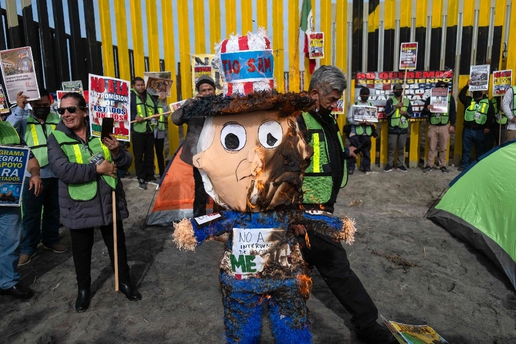 Al conmemorar el Día Internacional del Migrante, activistas y organizaciones de la sociedad civil que ayudan en Baja California a personas en tránsito se manifestaron ayer frente al Faro de Playas de Tijuana para exigir un alto a las deportaciones de Estados Unidos de indocumentados nacionales y extranjeros por las fronteras de México, además de quemar una piñata del ‘Tío Sam’. Foto Afp