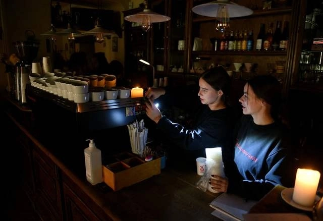 Empleadas de una cafetería laboran sin luz eléctrica en la ciuda de Lviv, Ucrania. Foto Afp