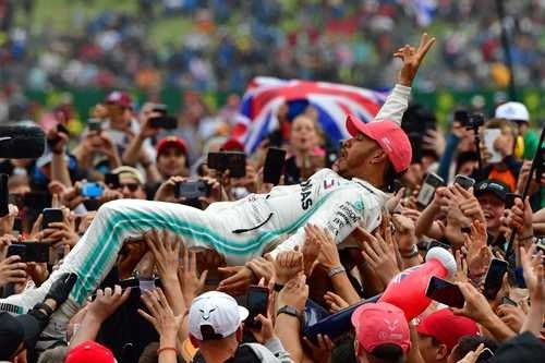 El piloto británico Lewis Hamilton es elevado por una ola de simpatizantes que celebra su victoria en el circuito de Silverstone en 2019. Foto Afp