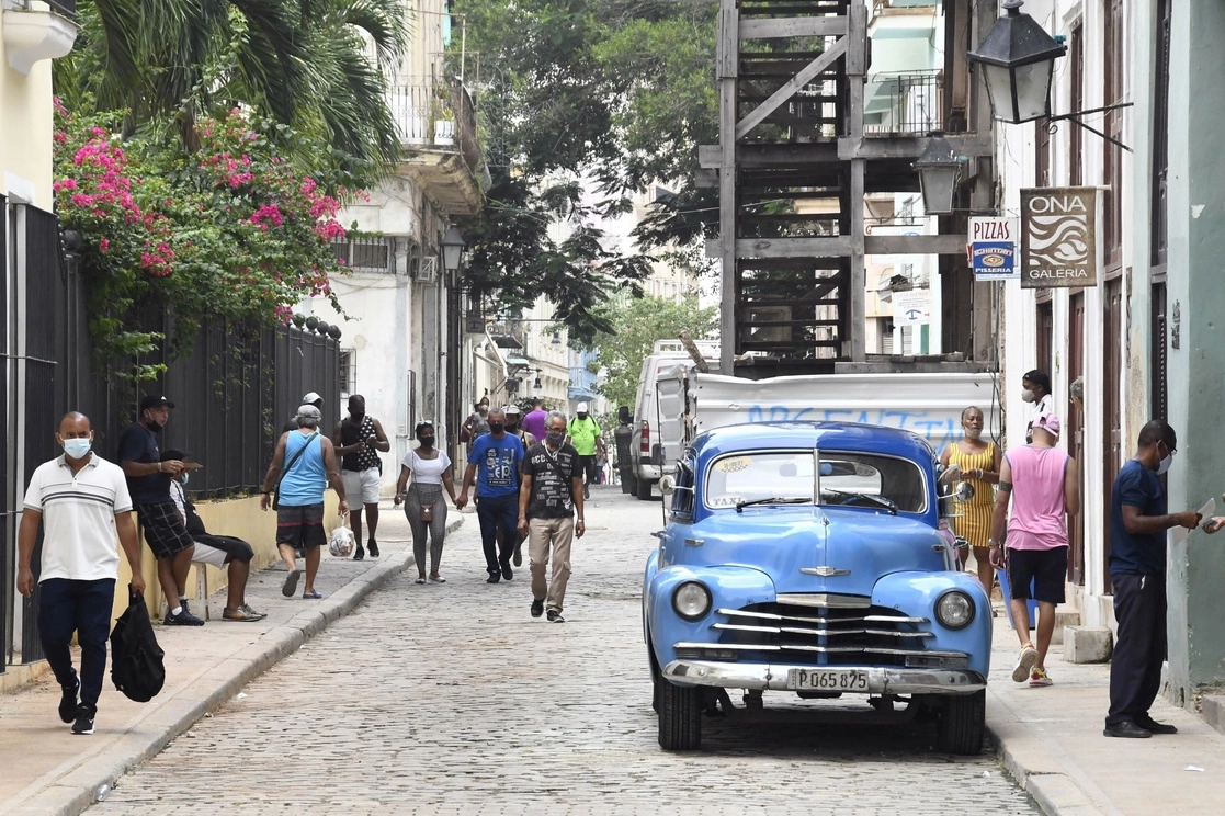 Personas caminan por una calle frente a un automóvil antiguo, en La Habana. Foto Xinhua