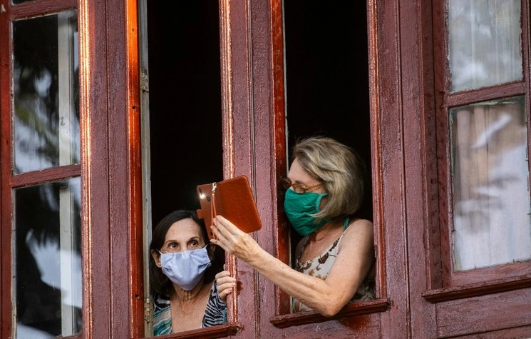 Dos mujeres conversan desde su vivienda en La Habana. Foto Ap