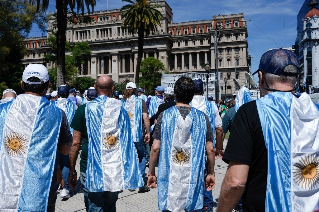 Manifestantes con banderas nacionales colocadas como capas protestan contra las reformas económicas del presidente argetino Javier Milei, frente a la Corte Suprema mientras los sindicatos impugnan legalmente las medidas, en Buenos Aires, ayer 27 de diciembre de 2023. Foto AP