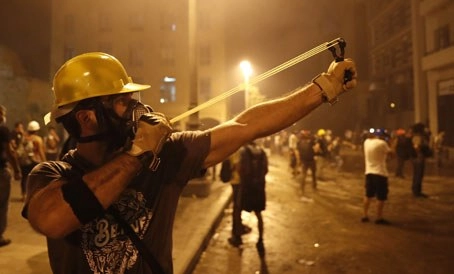 Manifestantes que intentaban llegar al Parlamento libanés responden a los disparos de gases lacrimógenos de la policía, en el segundo día de protestas antigubernamentales tras las devastadoras en Beirut. Foto Ap